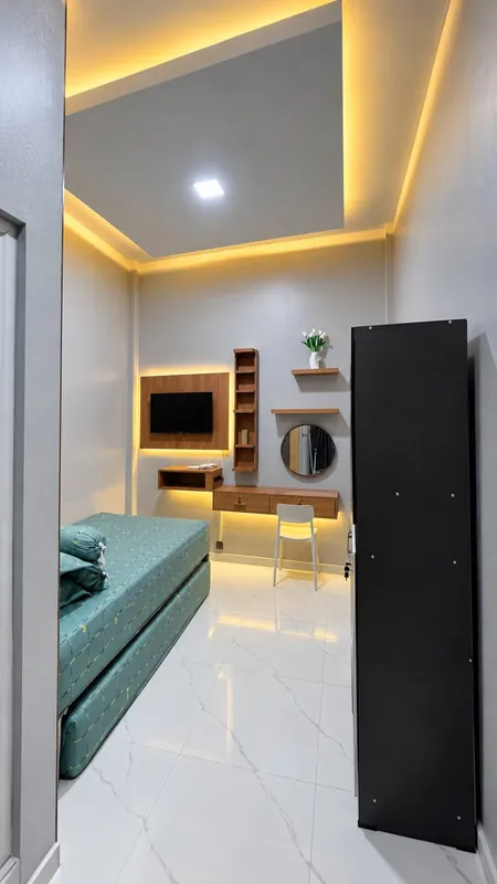 Interior kamar TIBANG GETKOST dengan kasur, meja belajar, dan TV